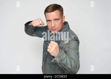 serious man stands in fighting stance isolated on gray background Stock Photo