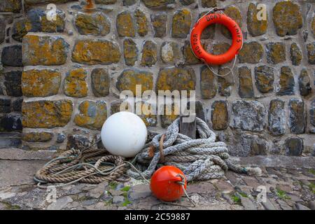 Rope, life ring and buoys on the stone harbour wall at Clovelly, North Devon. Stock Photo