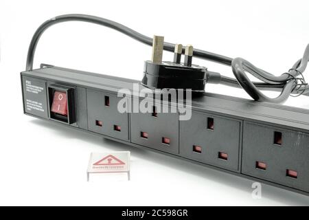 Isolated view of a 19-inch, rack mount power distribution socket showing its UK plug, sockets and illuminated on and off switch. Stock Photo
