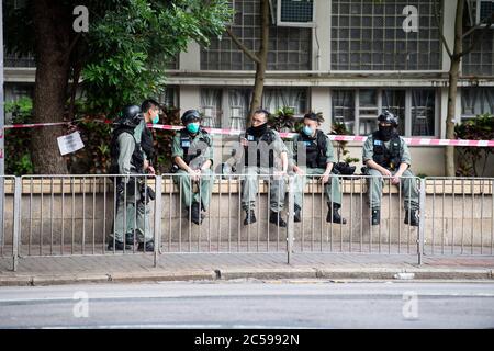 HONG KONG, HONG KONG SAR, CHINA: JULY 1st 2020.Police deal with the illegal protest march and are easily exhausted by the 34 Degree heat.Hong Kong Special Administrative Region Establishment Day. Twenty-three years after Hong Kong was handed by Britain back to Chinese rule, Beijing is pushing to implement tough new national security laws that will suppress the pro-democracy protests seen in the city. It will shatter the Sino-British Joint Declaration where China agreed to the One country, Two systems government. The banning of traditional marches for the first time, has infuriated the public.  Stock Photo