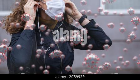 Covid-19 cells against woman in face mask wearing earphones Stock Photo