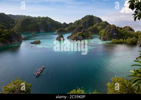 Indonesia, Papua, Piaynemo (Penemu), Raja Ampat Islands, view of the islands with a traditional boat Stock Photo
