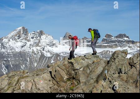 Switzerland, Valais, Trient Valley, the Marécottes, hikers descending the Luisin (2786m) towards the Col d'Emaney, in the background the Dents du Midi, with from left to right, the Haute Cime (3257m), the Doigt (3210m), the Dent Jaune (3186m), the Eperon (3114m), the Fortress (3164m) and the Cime de l'Est (3178m) Stock Photo