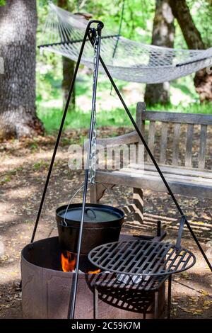 Tripod with dutch oven hanging over open fire Stock Photo