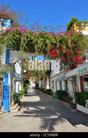 PUERTO DE MOGAN, GRAN CANARIA - FEB 19, 2014: Street with white houses colonia shown in Puerto de Mogan, Spain.  Favorite vacation place for tourists Stock Photo