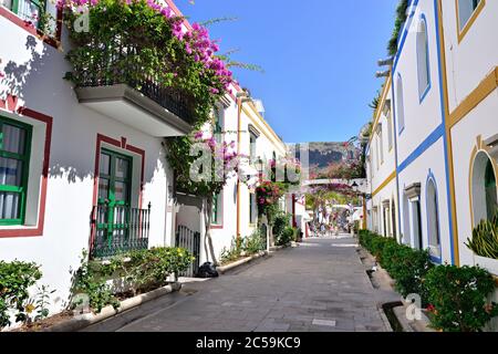 Street with white houses colonia shown in Puerto de Mogan, Spain.  Favorite vacation place for tourists and locals on island. Stock Photo