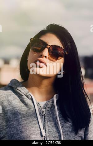 portrait of beautiful hispanic woman wearing sportswear and sunglasses Stock Photo