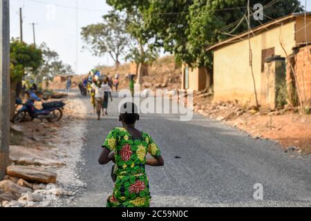 Africa, West Africa, Benin, Natitinqou. Young African girl running down the road. Stock Photo