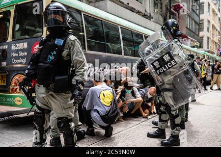 Riot police officers arresting protesters during the demonstration.Following the passing of the National Security Law that would tighten on freedom of expression, Hong Kong protesters marched on the streets to demonstrate. Protesters chanted slogans, sang songs, and obstructed roads. Later, riot police officers arrested several protesters using paintballs and pepper spray. Stock Photo