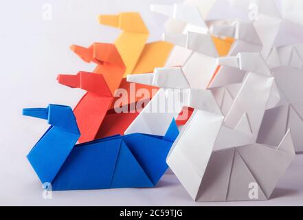 Team Work Concept using different color Origami Paper Swans. Achieve goals through collective efforts of a team Stock Photo