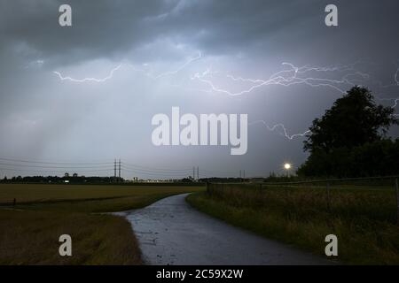 Lightning travels between the clouds from a thunderstorm over the countryside Stock Photo