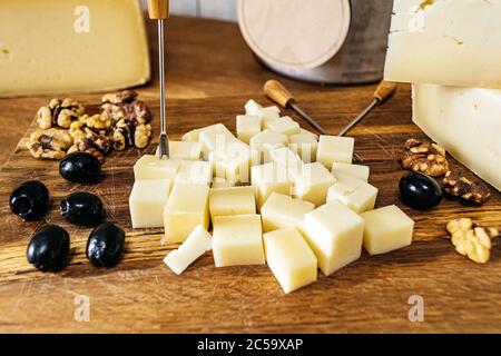 Sliced â€‹â€‹cheese, olives and nuts composition on a wooden table Stock Photo