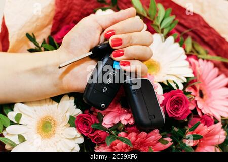 Car keys in a female hand with flowers Stock Photo