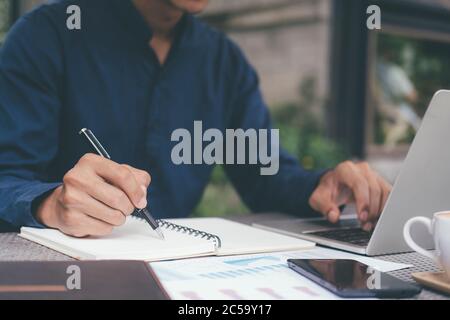 Closeup businessman writing hand and using computer outside the office. Stock Photo