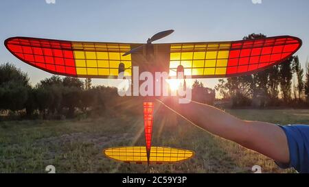 Closeup shot of a male hand holding an old red and yellow radio controlled guard plane Stock Photo