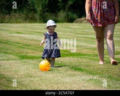 Toddler playing with a ball with mum, UK Stock Photo