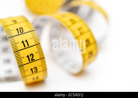 Yellow measuring tape on white background. Measurement of length and circumference. Lose weight and get fat. Stock Photo