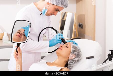 Young woman receiving face rejuvenation treatment on modern equipment at cosmetology clinic Stock Photo