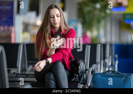 Woman with cellphone waiting for her plane at the airport Stock Photo