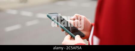 Man stands at crossroads with phone in his hands Stock Photo
