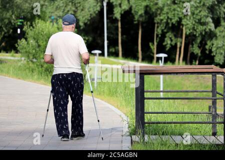 Nordic walking, elderly man walk with sticks in a summer park. Sports exercises for healthy spine and joints at spring, therapy for health Stock Photo