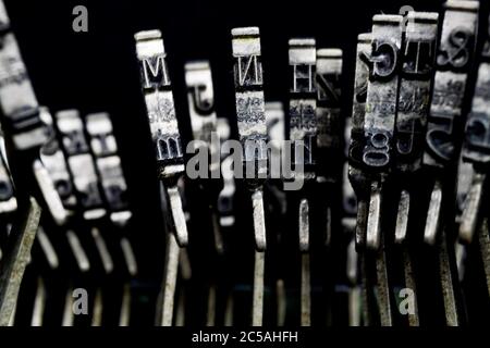 Macro closeup of isolated type bars of old typewriter with letters and symbols, black background Stock Photo