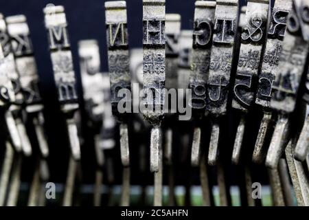 Macro closeup of isolated type bars of old typewriter with letters and symbols, black background Stock Photo