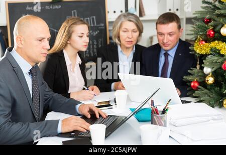 Confident businessman working with laptop on new business project with members of his team Stock Photo