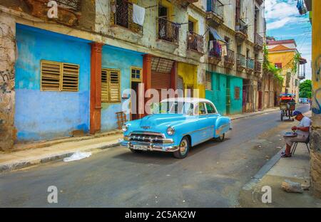 Havana, Cuba, July 2019, blue 50s Chevrolet car driving through a narrow street in the oldest part of the city