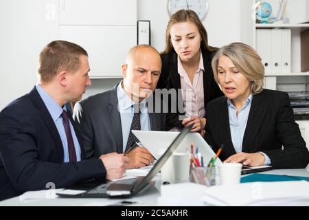 Successful coworkers engaged in business activities at common table in office Stock Photo