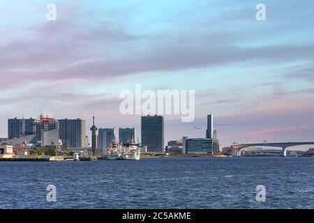 tokyo, japan - april 04 2020: Seascape of boats moored at Harumi Passenger Terminal on Tokyo Bay in front of the buildings of Ariake island at sunset. Stock Photo