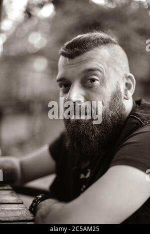 Man with a beard on a background of greenery. Large facial portrait of a bearded man of 40 years. Portrait full face. Stock Photo