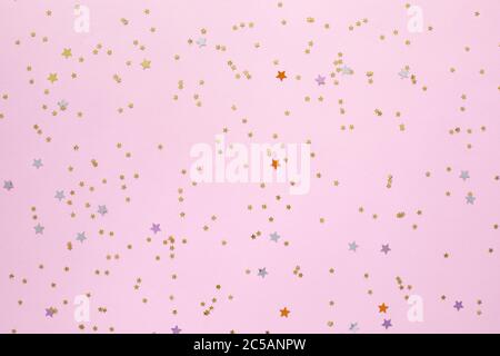 Golden stars shaped confetti glitter on pink background. Stock Photo