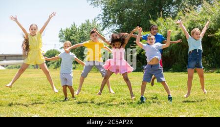 Happy school children jumping on the green lawn Stock Photo - Alamy