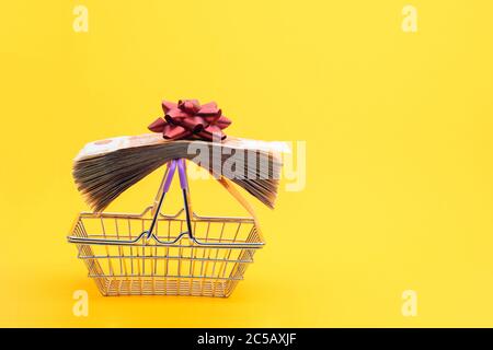 On the handles of the grocery cart lies a bundle of notes packed with gift ribbon and a red bow Stock Photo