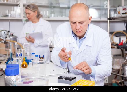 Experienced chemist working in research laboratory, analyzing liquid samples Stock Photo