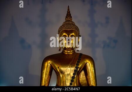 Closeup on a beautiful Buddha statue with interesting symmetry of shadows in the background. Stock Photo