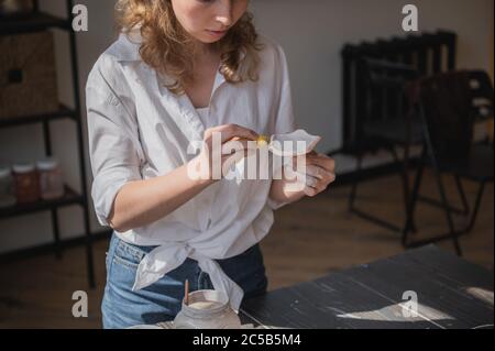 Production process of pottery. Application of glaze brush on ceramic ware. Stock Photo