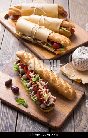 Fresh submarine sandwiches with varieties of fillings on wooden background Stock Photo