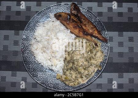 Peanut and coconut african kale stew and fried fish served with white rice Stock Photo