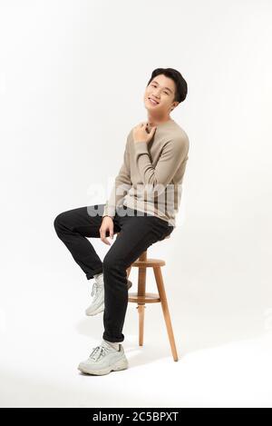 Full body Asian man sitting on high chair over white background Stock Photo