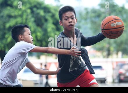 (200702) -- BEIJING, July 2, 2020 (Xinhua) -- Zhang Jiacheng (R) plays basketball with his schoolmate before morning class at a middle school in Gaocun Town of Yunfu City, south China's Guangdong Province, June 4, 2020. Zhang, 14, lost part of his right arm due to an accident in 2010. In 2018, he met with basketball for the first time on a free training class for children in summer vacation. With strong interest in basketball, Zhang has a dream to become a professional player and keeps practicing every day. His video of skillfully playing basketball with one arm went viral on internet, winni Stock Photo