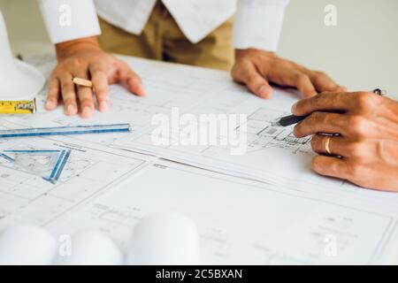 Two partnership architects or engineering working with blueprints and discussing project together at the meeting in the office. Stock Photo
