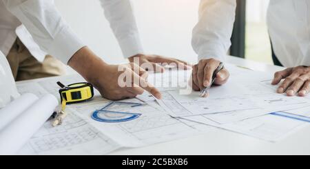 Two partnership architects or engineering working with blueprints and discussing project together at the meeting in the office. Stock Photo