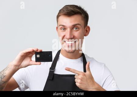 Cafe and restaurants, coffee shop owners and retail concept. Close-up shot of handsome salesman, store employee showing credit card, advertising Stock Photo