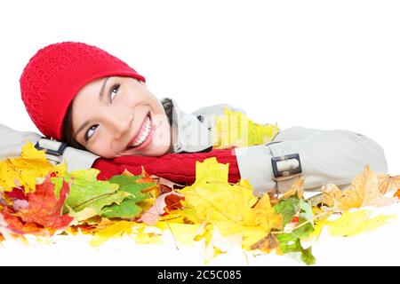 Fall woman happy with colorful Autumn leaves isolated on white background in studio. Thinking girl portrait close up resting face on leaves looking up. Mixed race Asian Caucasian female model Stock Photo