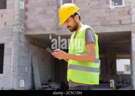 Young carpenter is using mobile phone at carpentry shop Stock Photo