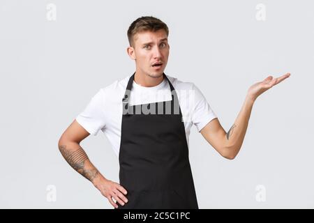 Employees, grocery stores and coffee shop concept. Disappointed and annoyed waiter, barista pointing right and looking displeased, complaining over Stock Photo