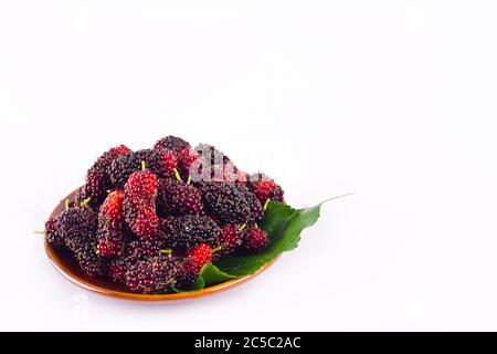 ripe berry fruit and mulberry leaf  in brown bowl on white background healthy mulberry fruit food isolated Stock Photo