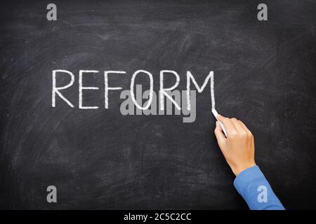 Reform blackboard - education reform or other. Hand writing REFORM with chalk on black chalkboard. Stock Photo